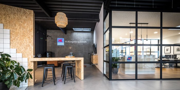 Der Empfangsbereich zeigt eine moderne Einrichtung mit Holz- und Metallakzenten sowie einer großen Fensterfront.