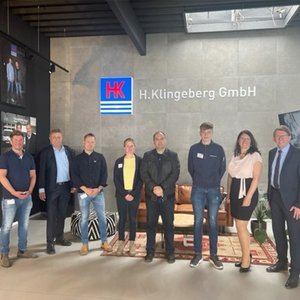 Eine Gruppe von sieben Personen steht vor der Wand mit dem Logo von H. Klingeberg GmbH in einem modernen Büro.