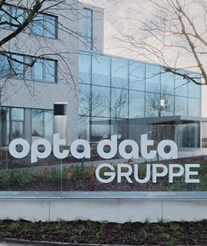 Das moderne Gebäude der opta data Gruppe mit großen Glasfenstern und einem klaren, minimalistischen Design ist gut sichtbar.
