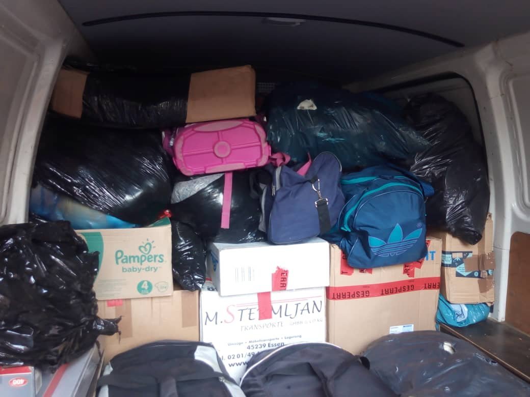 Der Kofferraum eines Fahrzeugs ist überfüllt mit schwarzen Müllsäcken, Kisten und verschiedenen Taschen.