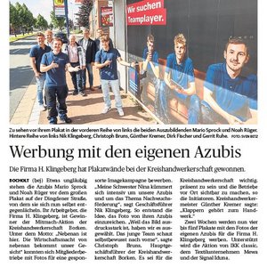 Sechs junge Männer stehen vor einem Plakat, das für die Firma H. Klingberg wirbt, und lächeln in die Kamera.