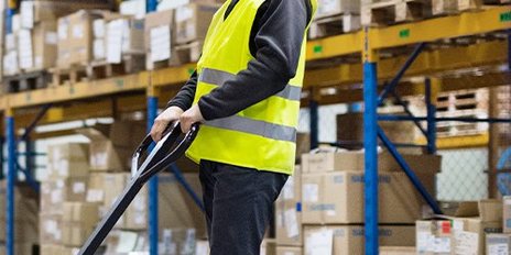 Ein Lagerist bedient einen Hubwagen in einer Lagerhalle