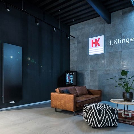 Ein modernes Büro mit einem braunen Ledersofa, einem runden Tisch und einer Pflanze auf einem minimalistischen Teppich.